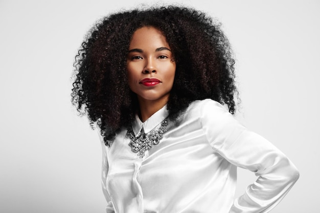 Mujer negra con camisa blanca y pelo rizado.