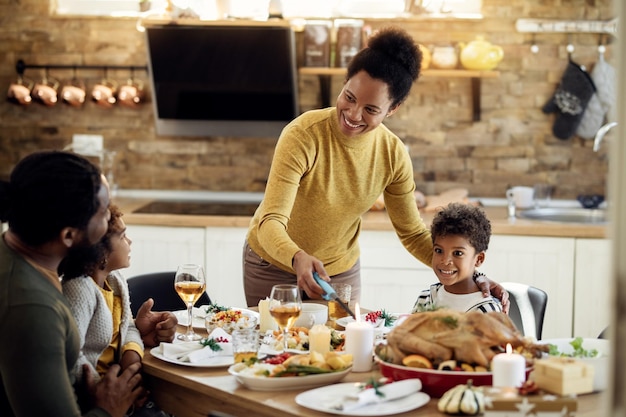 Mujer negra feliz encendiendo velas durante el almuerzo familiar en Navidad