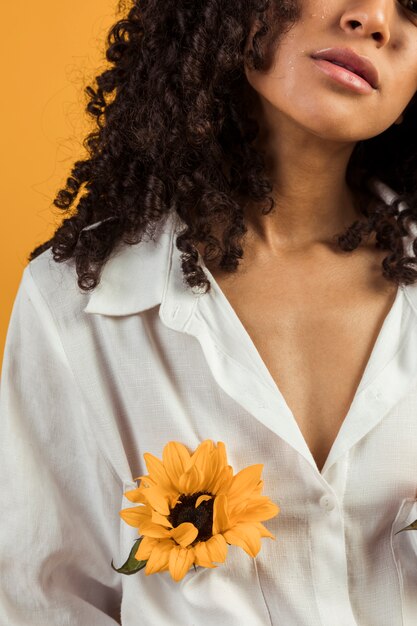 Mujer negra con flor amarilla en el bolsillo de la camisa.