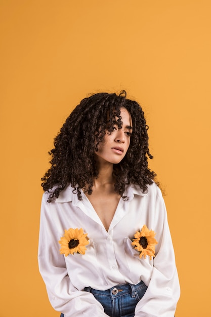 Mujer negra con flores en bolsillos de camisa.