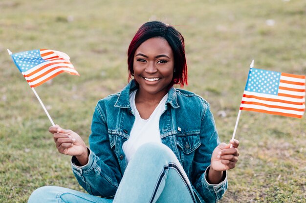 Mujer negra joven sonriente con las banderas americanas