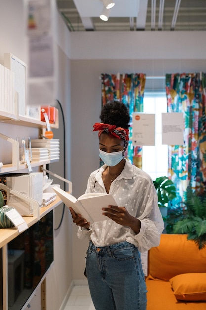 Mujer negra leyendo un libro en una librería durante el período de cuarentena