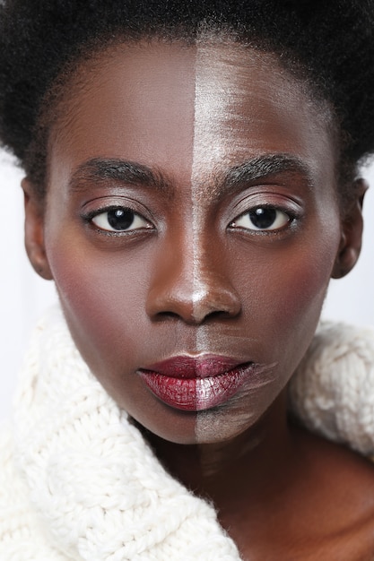 Mujer negra con media cara en maquillaje, concepto de belleza