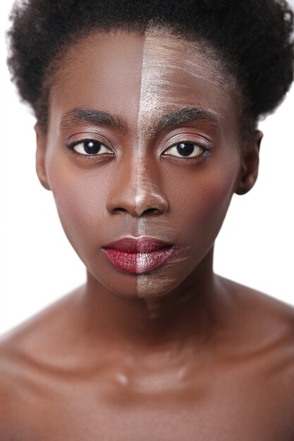 Mujer negra con media cara en maquillaje, concepto de belleza