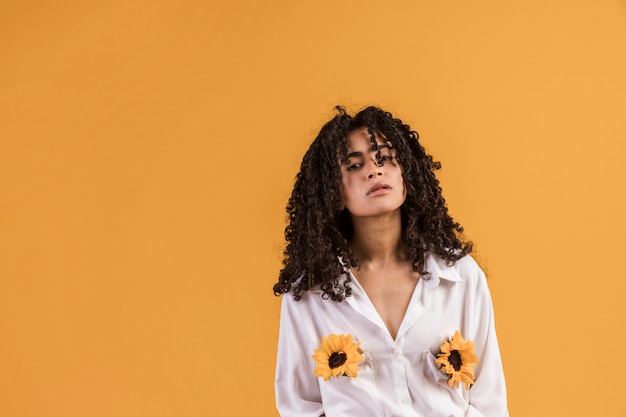 Mujer negra pensativa con flores en bolsillos de camisa