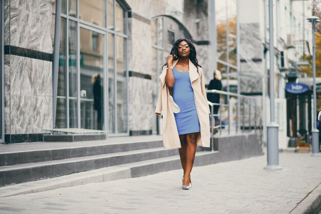 Mujer negra de pie en una ciudad de otoño