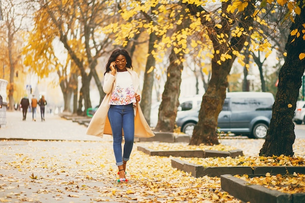 Mujer negra de pie en una ciudad de otoño