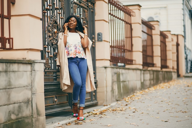 Mujer negra de pie en una ciudad de otoño