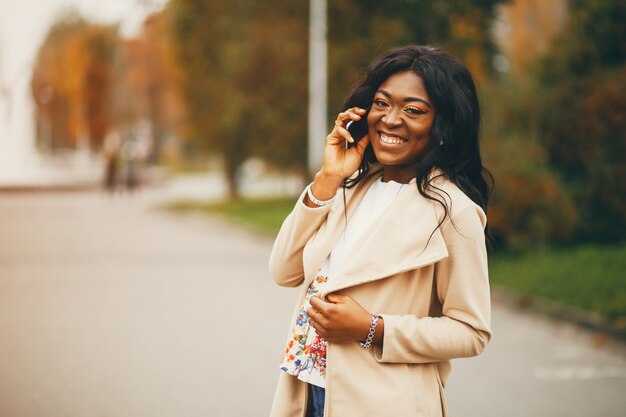 Mujer negra de pie en una ciudad de otoño