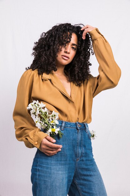 Mujer negra de pie con flores de Margarita en el bolsillo de los pantalones vaqueros