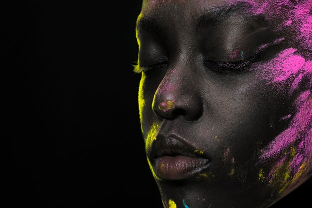 Mujer negra posando con polvo rosa y amarillo.