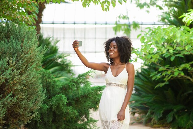 Mujer negra positiva que toma la foto de Selfie en parque