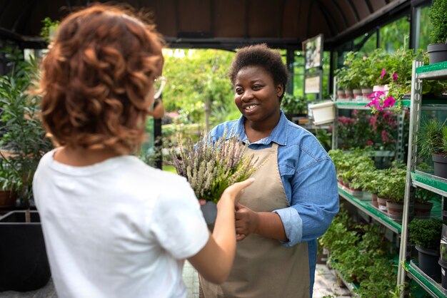 Mujer negra que dirige un negocio de flores plano medio