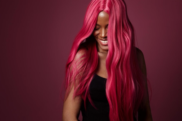 Mujer negra de raza mixta con cabello rosado feliz sonriendo creativo color de cabello