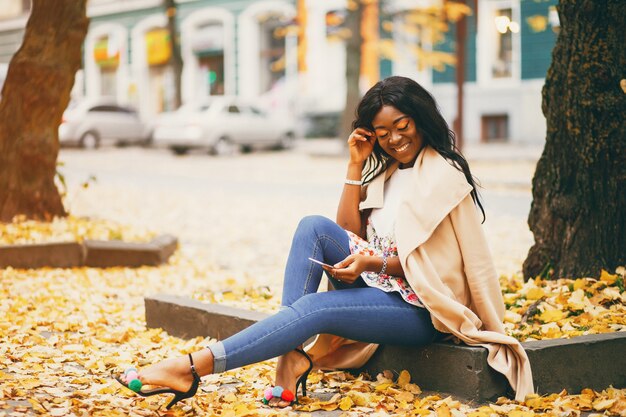 Mujer negra sentada en una ciudad de otoño