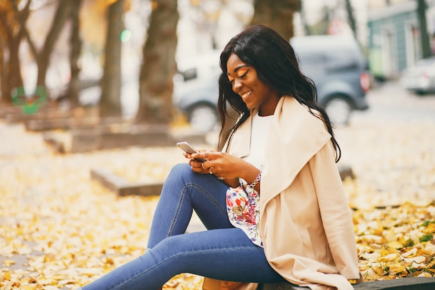 Mujer negra sentada en una ciudad de otoño