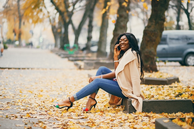 Mujer negra sentada en una ciudad de otoño