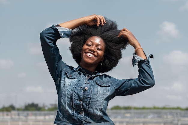 Mujer nigeriana sonriente de tiro medio posando afuera