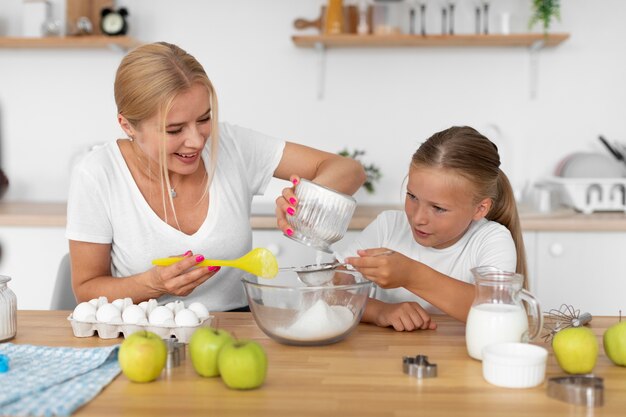 Mujer y niña cocinando plano medio