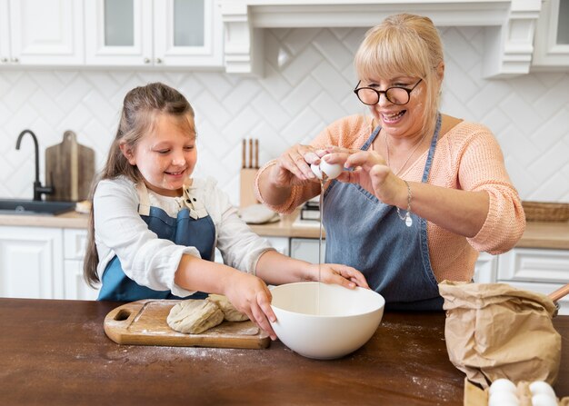 Mujer y niña cocinando plano medio