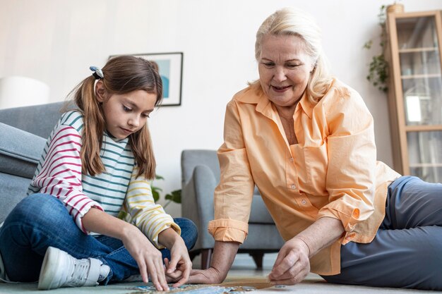 Mujer y niña haciendo rompecabezas en el piso