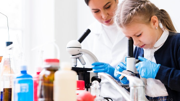 Mujer y niña con microscopios de primer plano