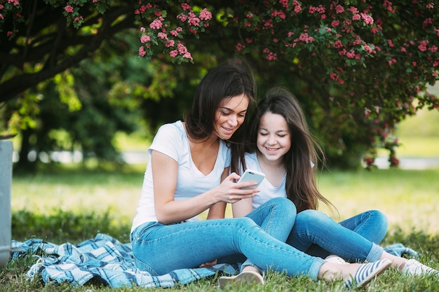 Mujer y niña en el parque con smartphone