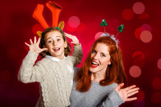 Mujer y niña pequeña con adornos de navidad en sus cabezas