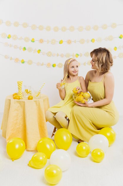 Mujer y niña posando mientras sostiene limones