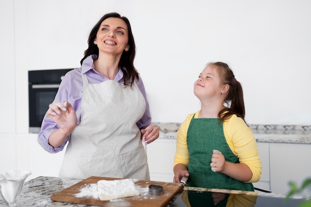 Foto gratuita mujer y niña sonrientes de tiro medio en la cocina