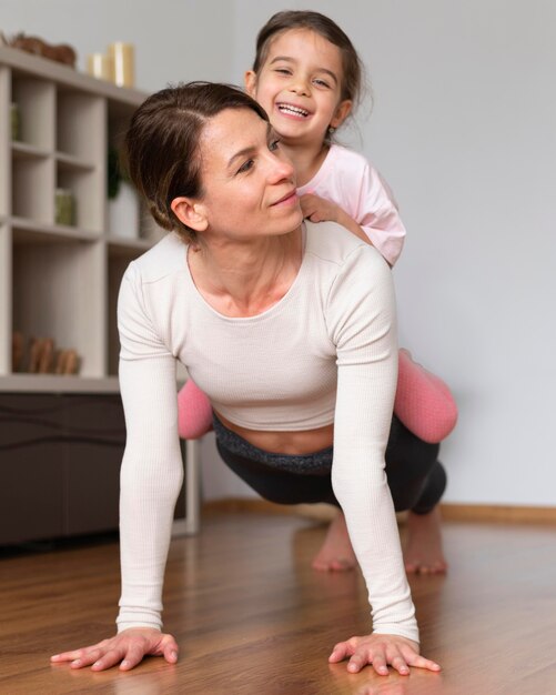 Mujer y niña de tiro completo haciendo ejercicio juntos