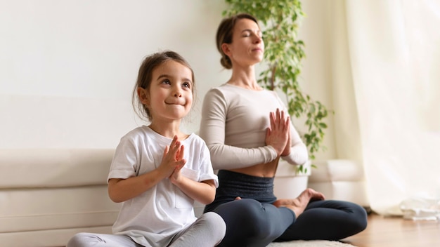 Mujer y niña de tiro completo meditando