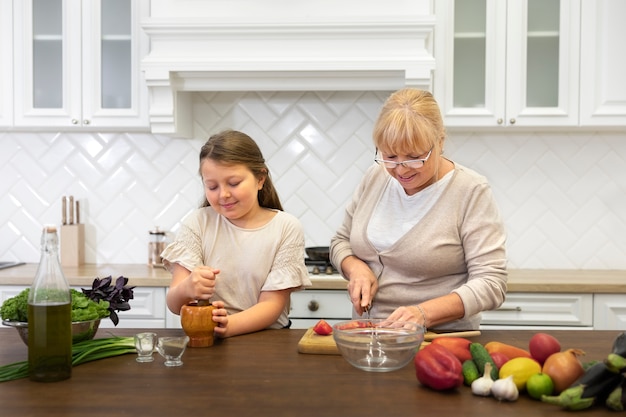 Mujer y niña de tiro medio cocinando