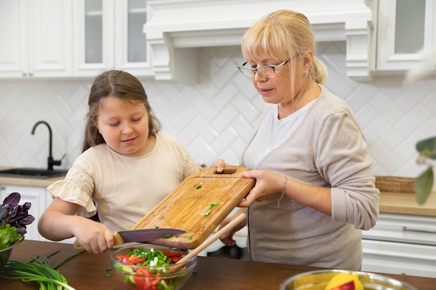 Mujer y niña de tiro medio cocinando