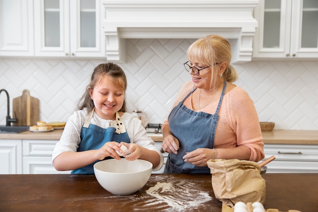 Mujer y niña de tiro medio cocinando