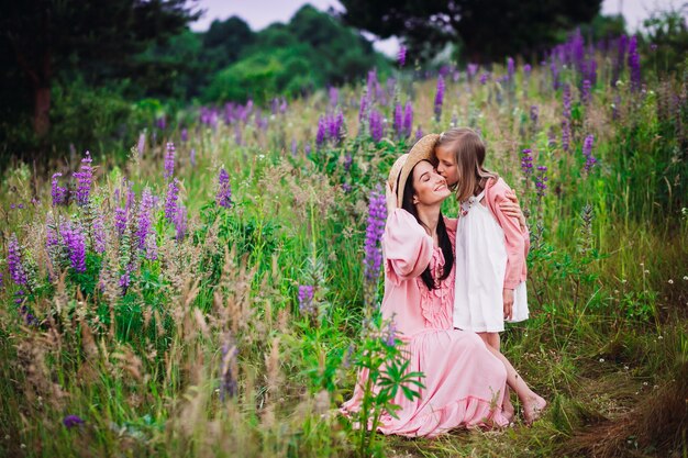 La mujer y la niña en vestidos de color rosa posan en el campo de lavanda