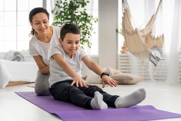 Mujer y niño en estera de yoga full shot