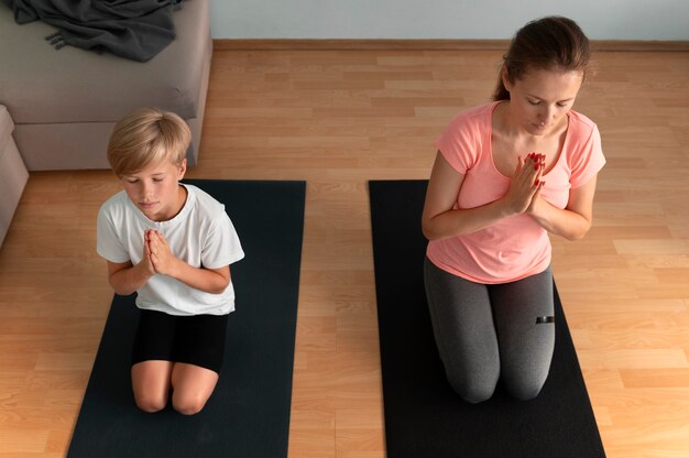 Mujer y niño en estera de yoga full shot