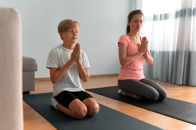 Mujer y niño meditando tiro completo