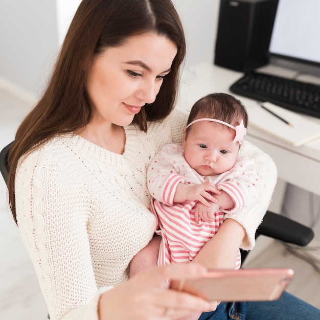 Foto gratuita mujer y niño pequeño que miran smartphone