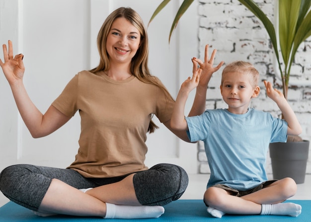 Foto gratuita mujer y niño sonriente de tiro completo en estera