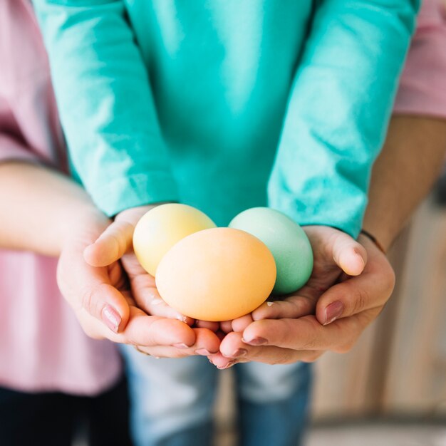 Mujer y niño sosteniendo huevos de Pascua en manos