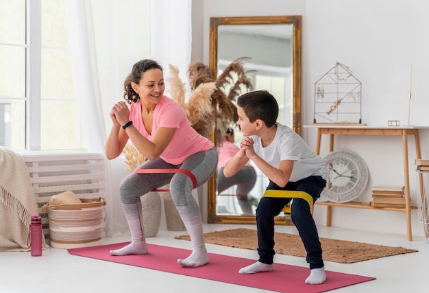 Foto gratuita mujer y niño de tiro completo entrenando con banda de resistencia