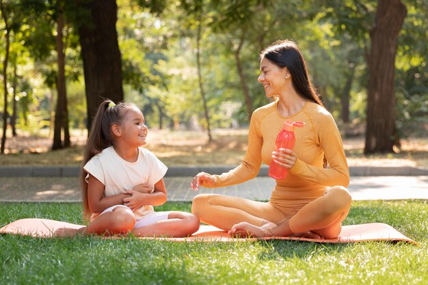 Mujer y niño de tiro completo en estera de yoga