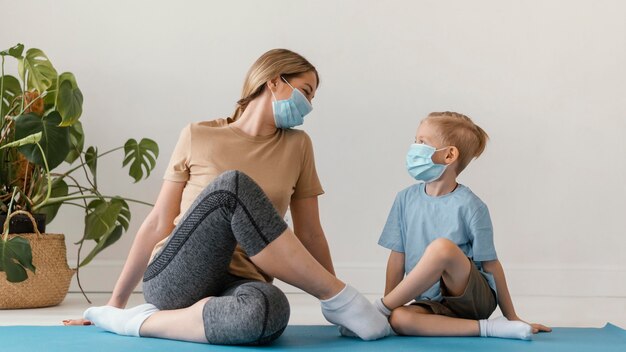 Mujer y niño de tiro completo con máscaras faciales