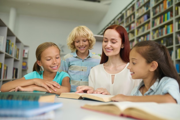 Mujer y niños leyendo libros juntos