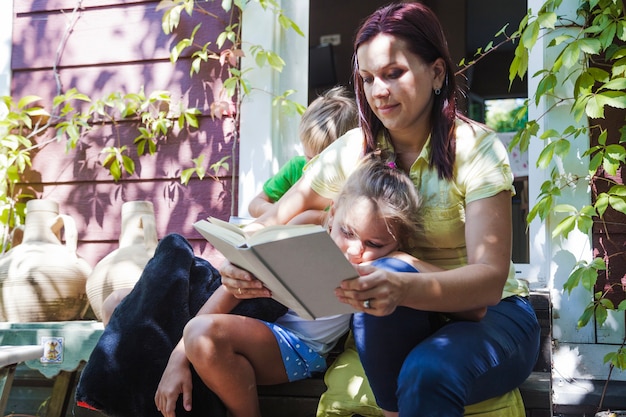 Mujer con los niños que leen en el pórtico