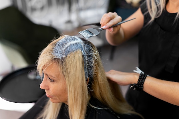 Mujer obteniendo su cabello teñido en el salón de belleza