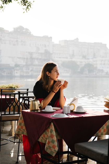 Mujer occidental que tiene un teatime en un café en Udaipur