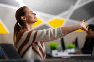 Foto gratuita mujer en la oficina estirándose durante un día de trabajo